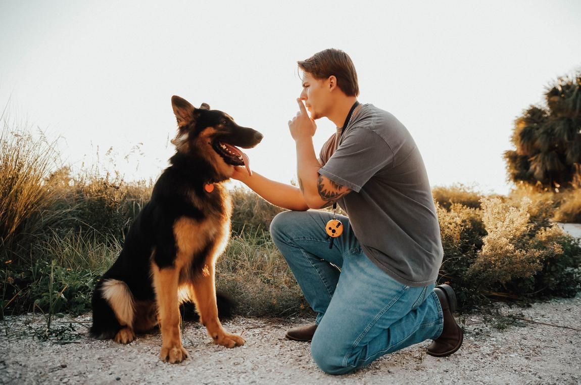 Jacob Soos giving a hand-signal cue to a German Shepherd during training